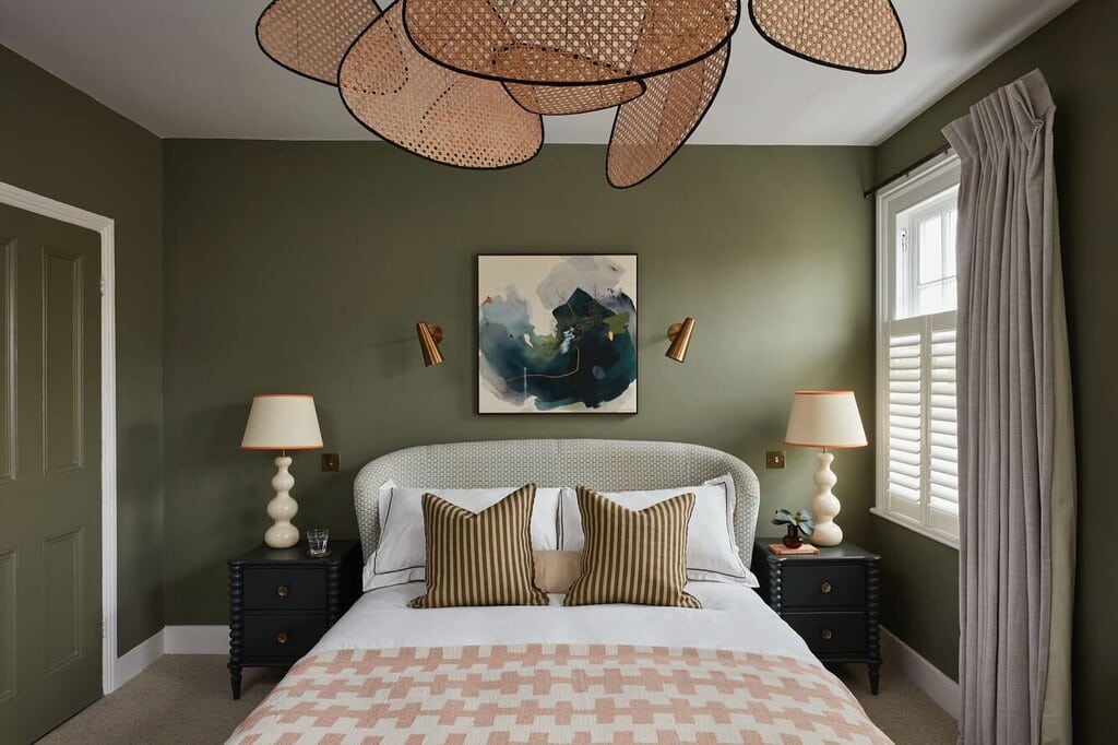 Olive green bedroom with Farrow & Ball Treron walls, a patterned headboard, cream lamps and striped cushions