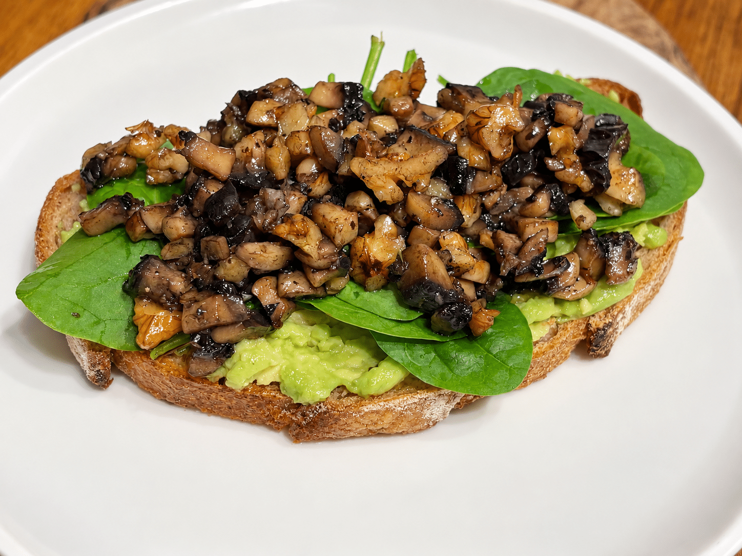 Mushroom on toast with toasted walnuts, baby spinach and smashed avocado on sourdough